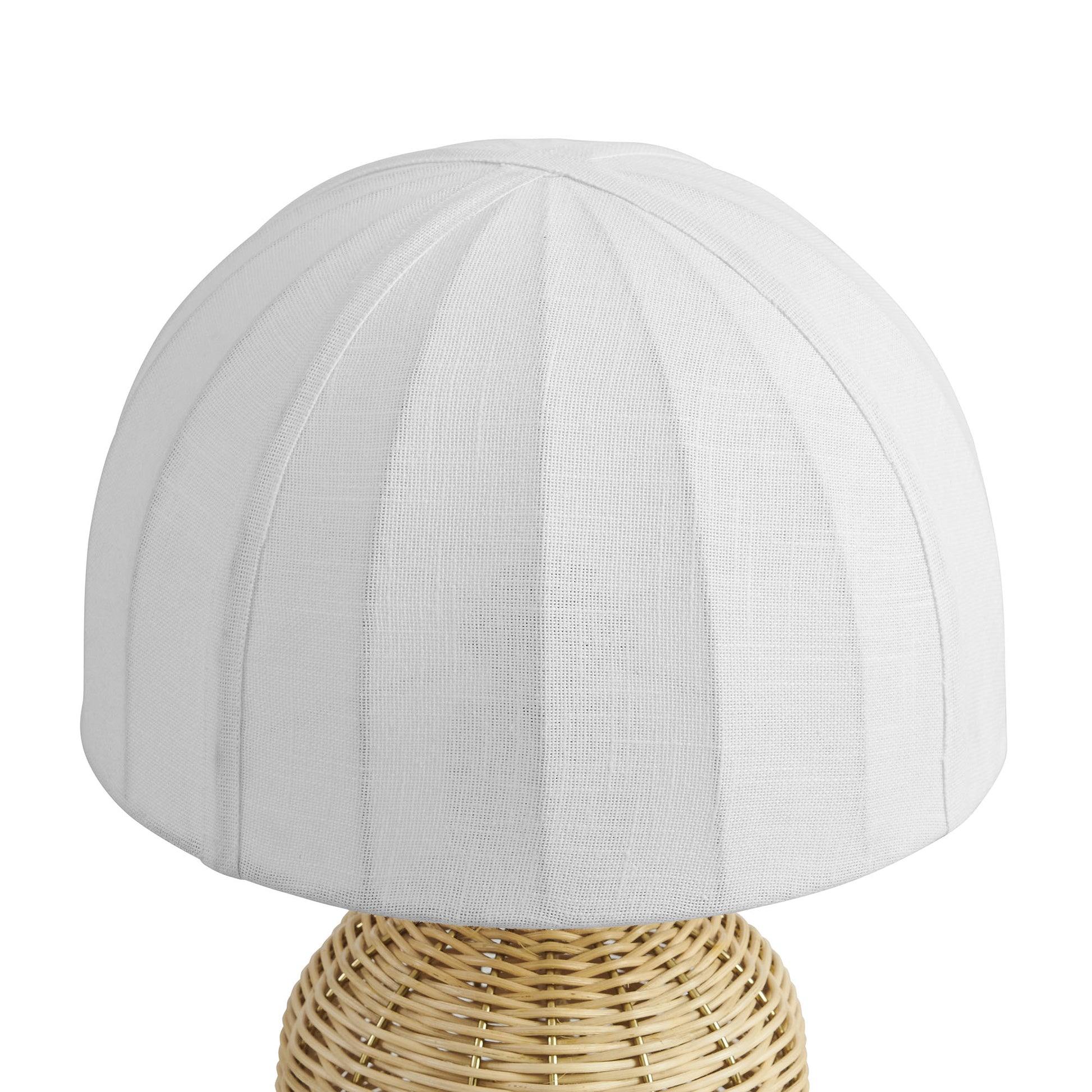 White fabric dome lampshade with vertical seam panels on a natural woven rattan table lamp base.