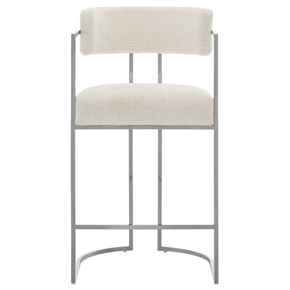 Gray metal bar stool with cream upholstered seat and backrest, curved footrest, modern industrial design.