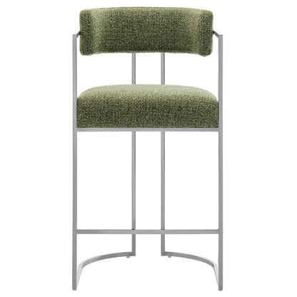 Olive green textured fabric cushioned counter stool with curved backrest on a slim gray metal frame.