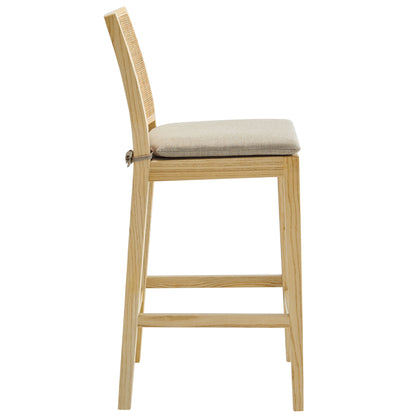 Natural wood counter stool with beige cushioned seat and woven cane back, slim frame with footrest.