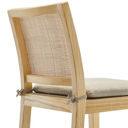 Natural wood and rattan counter stool with a caned back and beige upholstered seat cushion.