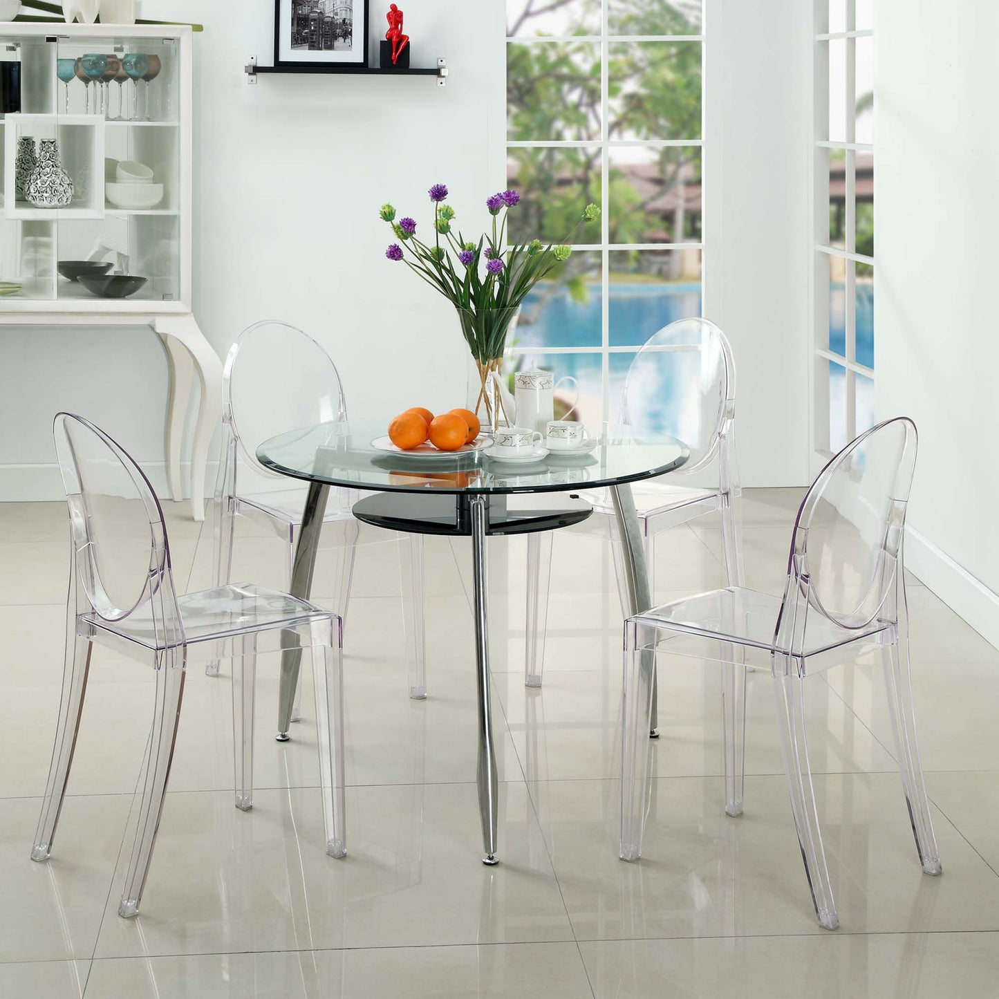 Clear acrylic ghost dining chairs (set of 4) in a bright modern dining room, with a vase of purple flowers and oranges on the table