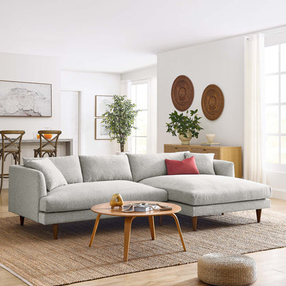 Right-facing gray sectional sofa with wooden legs in a bright mid-century living room; round wooden coffee table on a jute rug, red accent pillow.