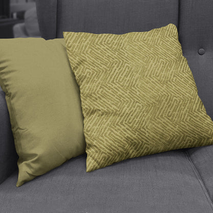 Olive green velvet throw pillow beside a mustard-yellow geometric zigzag patterned pillow on a gray sofa.