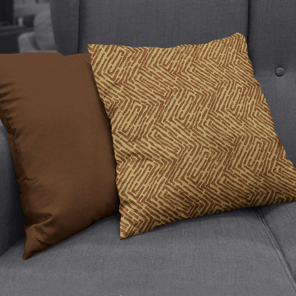 Two square throw pillows on a gray sofa: a solid brown pillow on the left and a tan pillow with a brown geometric pattern.