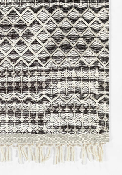 Black and ivory geometric woven rug with diamond lattice, decorative bands, and fringe tassels.