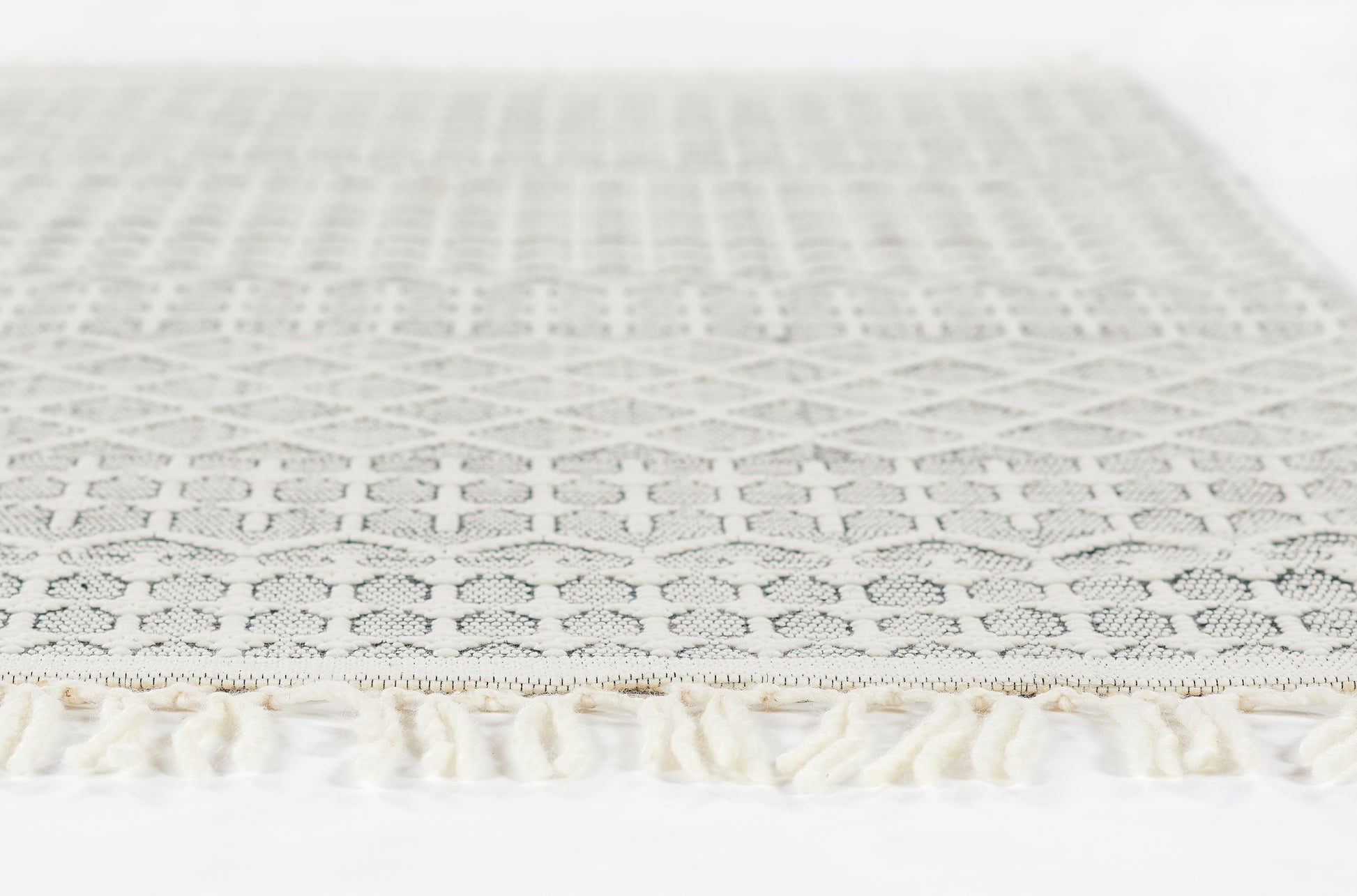Light gray lace rug, 2' x 3', with geometric diamond pattern and cream fringe
