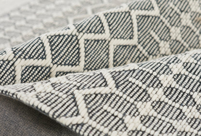 Dark gray and white woven throw blanket with geometric diamond and zigzag pattern, folded.