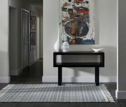 2' x 3' gray woven rug in entryway, with white vases, a bowl, and abstract artwork above.