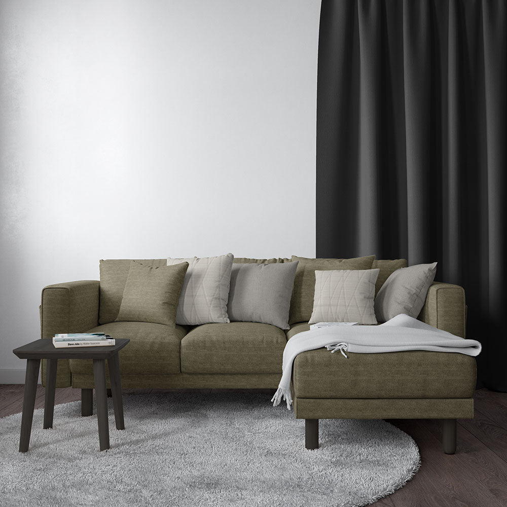 Olive-green fabric sectional with chaise, neutral beige/gray cushions, white throw blanket, dark wood legs, round side table, gray rug.