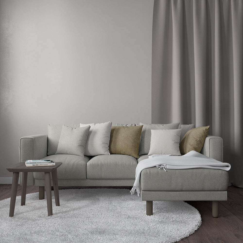 Light gray L-shaped fabric sectional with chaise, neutral cushions, wooden side table, soft rug, gray curtains