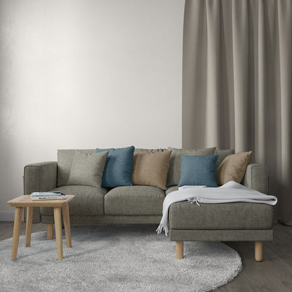 Grey sectional sofa with blue and tan cushions, chaise on the right, light wood legs, round coffee table and soft rug.
