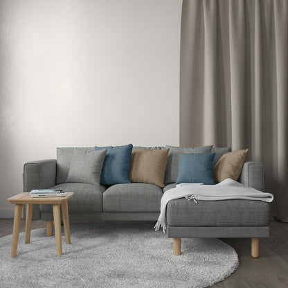 Grey solid fabric upholstery in a living room scene; visible is a gray sectional sofa with blue and tan cushions, light wood legs, a white throw blanket, and a round wooden side table on a gray rug.