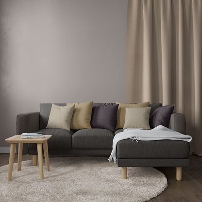 Charcoal gray sectional sofa with light wood legs, mixed cushions, cream throw, round beige rug, wooden side table.