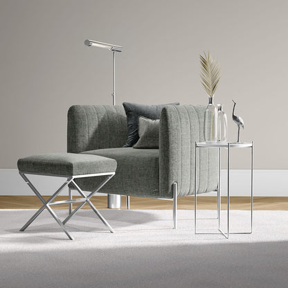 Grey fabric modular sofa with matching ottoman, chrome legs, glass side tables and a floor lamp in a modern living room.