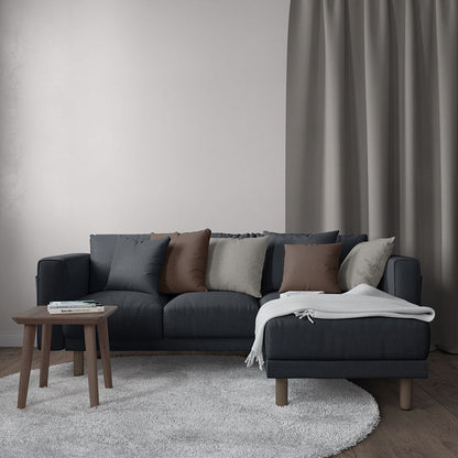Charcoal sectional sofa with chaise, brown/gray cushions, white throw; wooden legs, small coffee table, light gray rug.