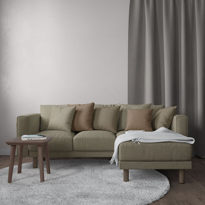 Olive-green fabric sectional sofa with beige cushions and a chaise, a wooden coffee table, and a gray rug in a neutral living room.