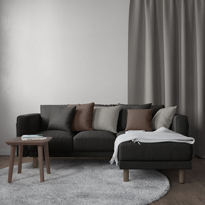 Charcoal sectional upholstered in solid textured fabric; cushions in gray and brown, chaise with a light gray throw; round wood coffee table on a soft gray rug.