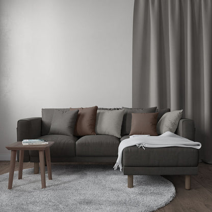 Charcoal gray sectional with chaise, brown and gray cushions, wood legs, gray rug, wooden side table, white throw blanket.