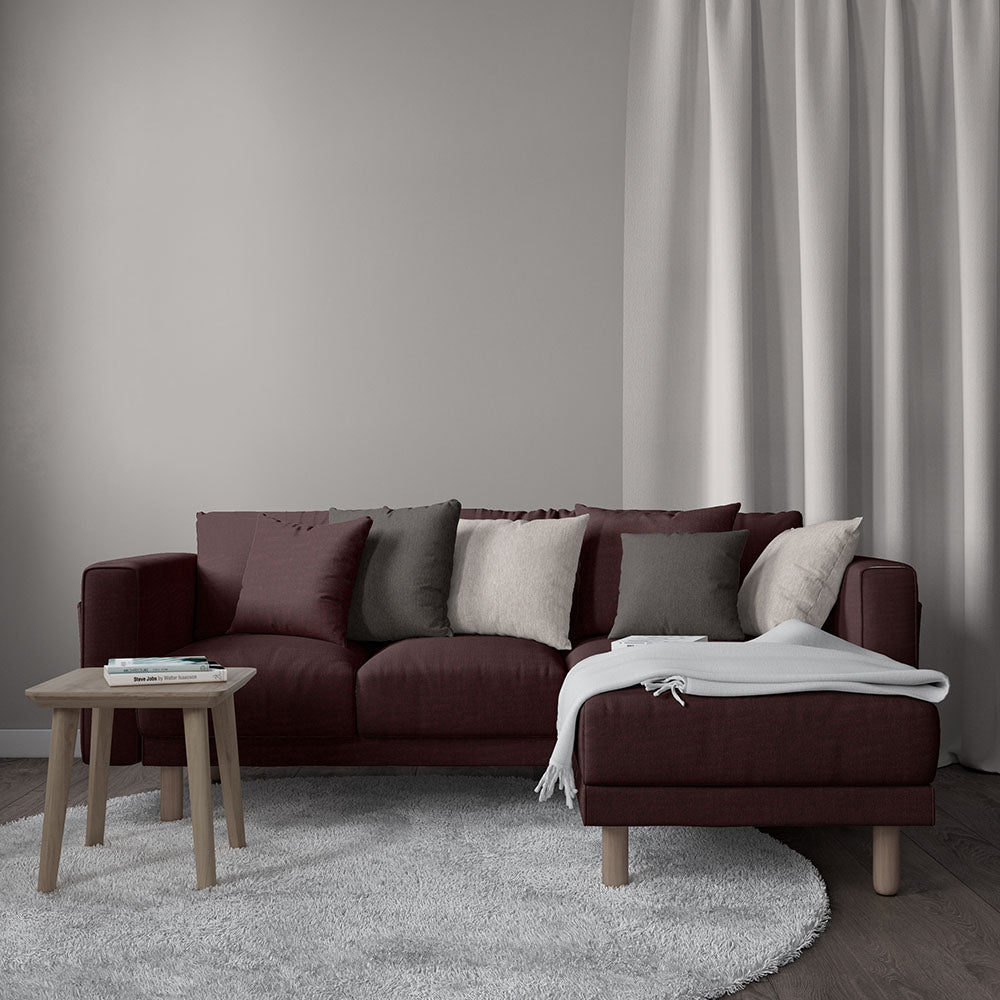 Deep burgundy sectional with chaise, neutral cushions, light wood legs, white throw, round coffee table, gray shag rug
