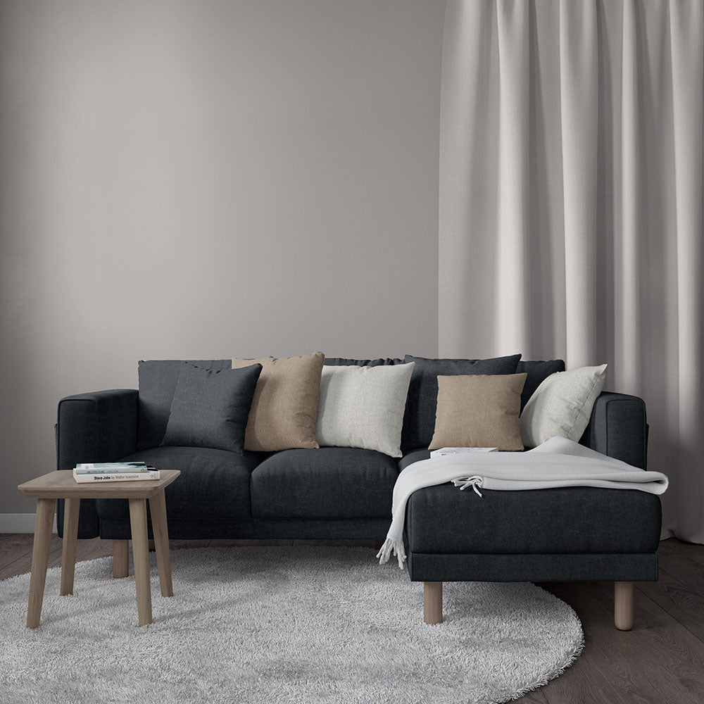 Slate blue solid fabric L-shaped sofa with light wood legs, beige cushions, white throw, wood coffee table in a modern living room.