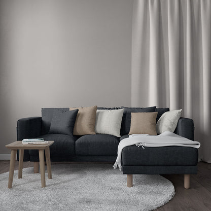 Slate blue solid fabric L-shaped sofa with light wood legs, beige cushions, white throw, wood coffee table in a modern living room.