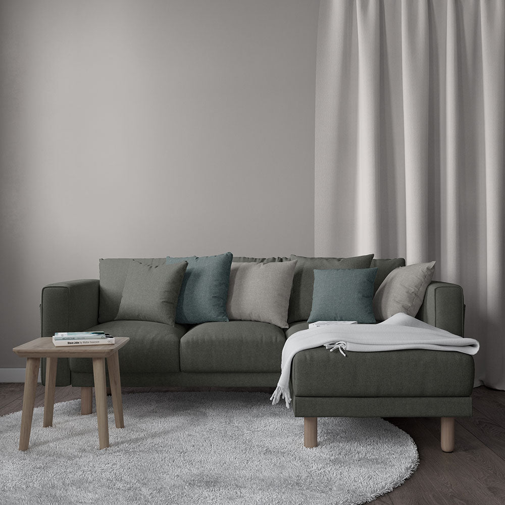 Gunmetal solid fabric sectional sofa with right chaise, teal/gray cushions, white throw, round wood coffee table; minimalist living room