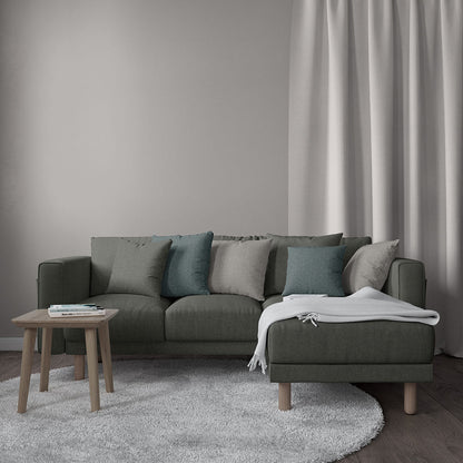 Gunmetal solid fabric sectional sofa with right chaise, teal/gray cushions, white throw, round wood coffee table; minimalist living room