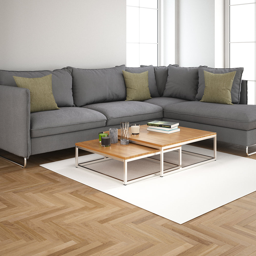 Modern gray sectional sofa with green accent pillows and a two-tier wood-top coffee table on a white rug in a bright living room.