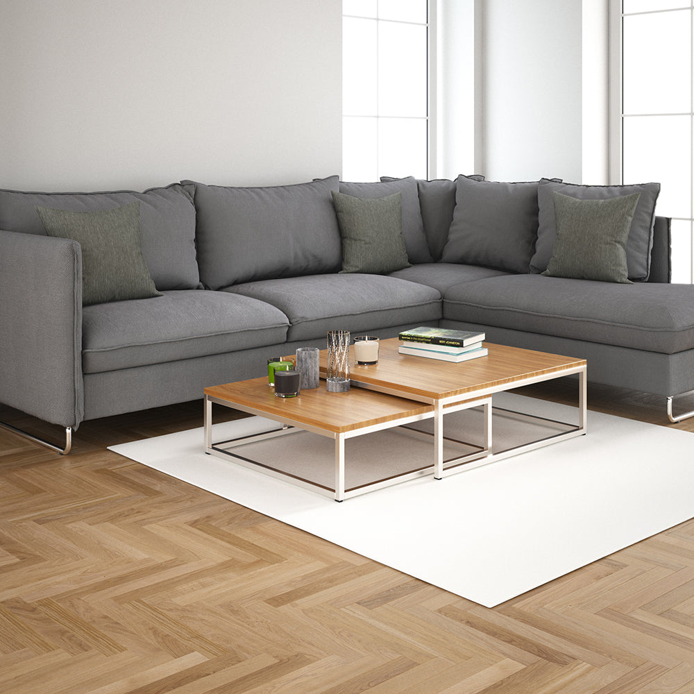 Modern gray L-shaped sofa with greenish cushions, two-tier wood-and-metal coffee table on a white rug in a bright living room.
