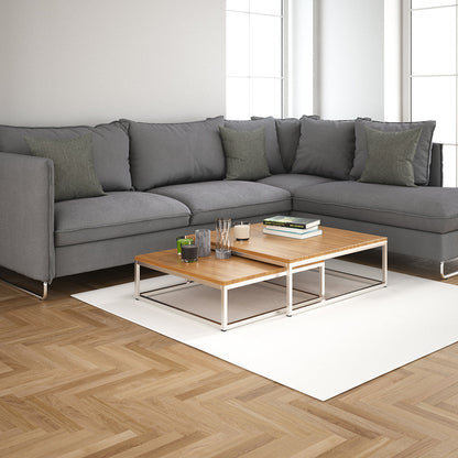 Modern gray L-shaped sofa with greenish cushions, two-tier wood-and-metal coffee table on a white rug in a bright living room.