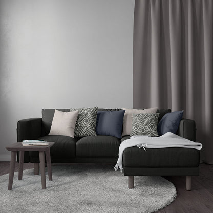 Dark gray sectional sofa with mixed geometric pillows, light throw, small round coffee table, gray rug & curtains.