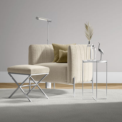 Beige linen-solid fabric upholstery on a sofa with ottoman and chrome legs, in a living room setup with glass side tables, a floor lamp, and a decorative vase with reeds.