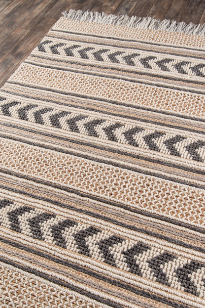 Beige and black striped woven rug with chevron motifs, fringe edge, on wood floor; rustic boho style.