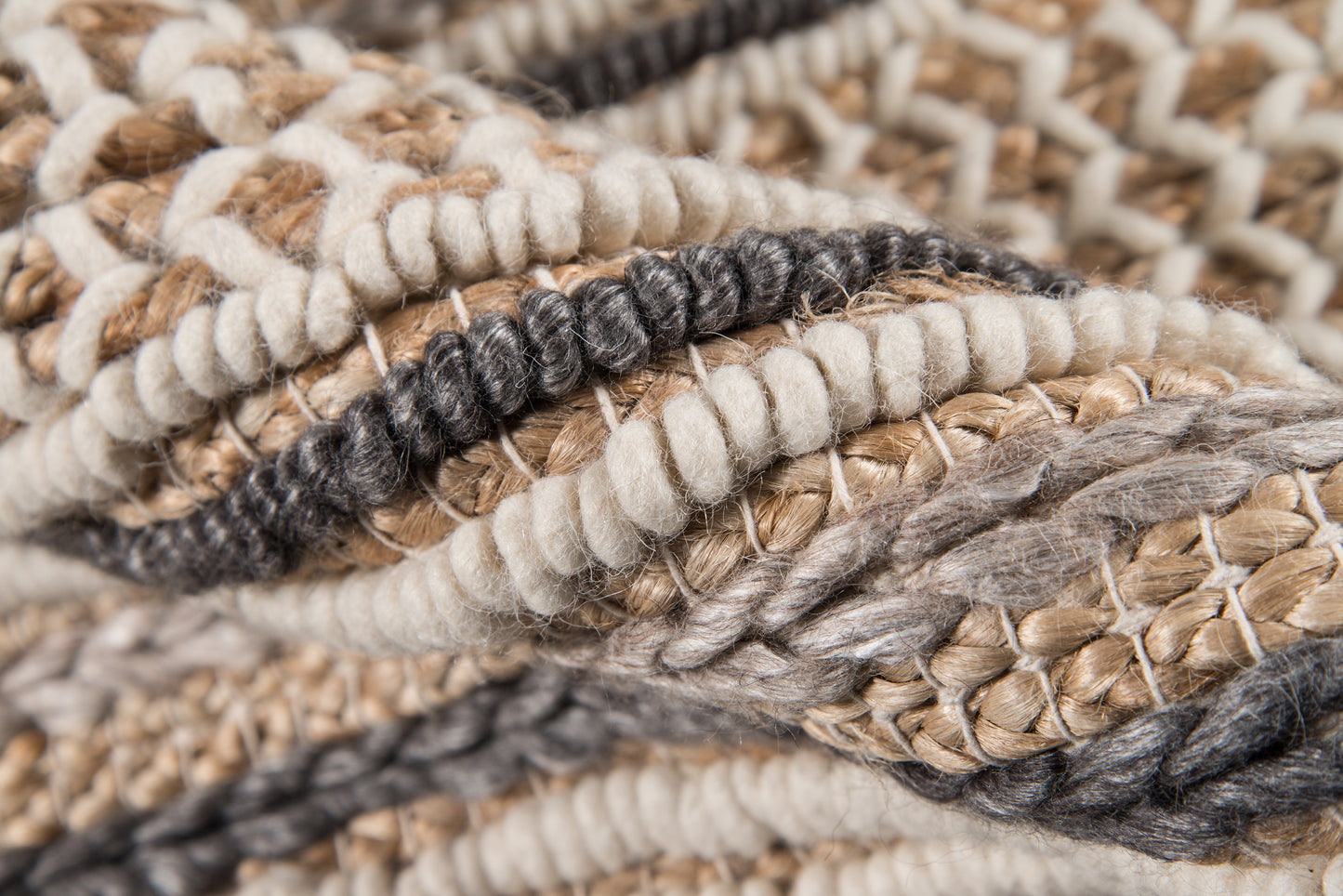 Close-up of a chunky braided wool rug/throw in beige, ivory, taupe and gray tones.