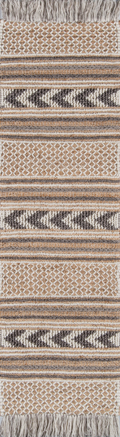 Woven rug featuring beige, cream, taupe and black geometric stripes, chevron and honeycomb motifs with a fringed top.