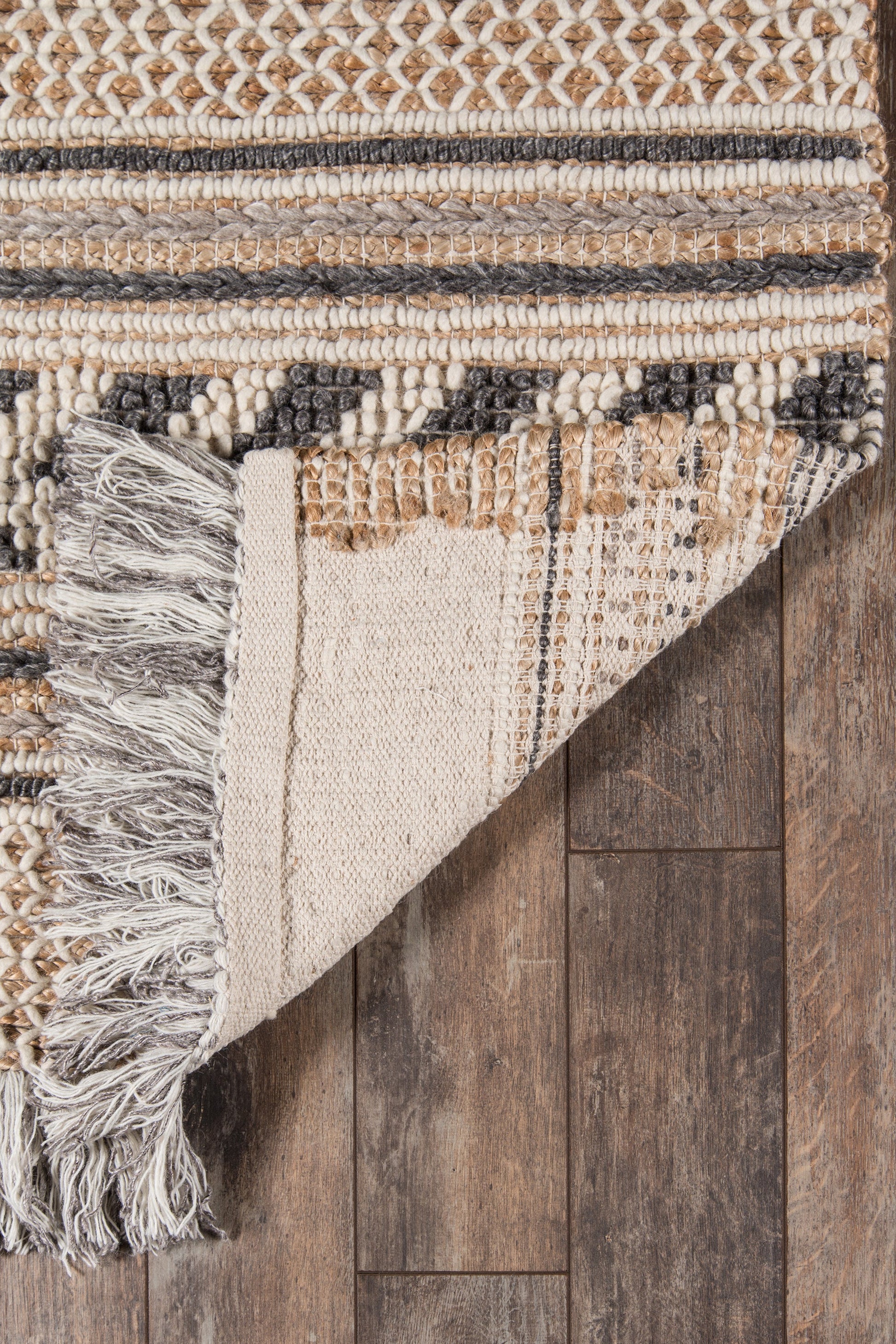Neutral woven rug with cream, beige and gray stripes, fringe along edge; geometric pattern, boho living-room style.