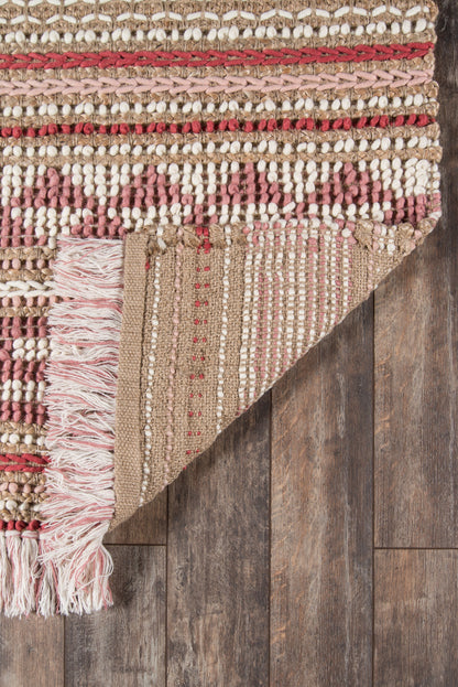 Woven beige and brown rug with pink stripes and fringe tassels, folded at corner on dark wood floor.