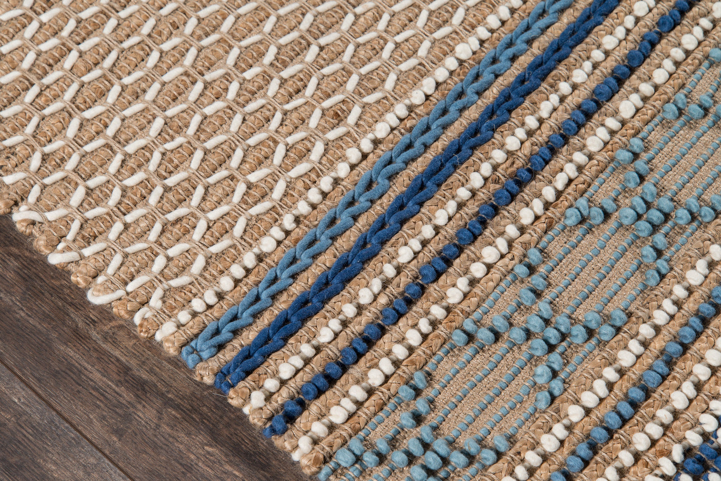 Handwoven natural beige rug with blue braided stripes and white knotted accents on a wooden floor.