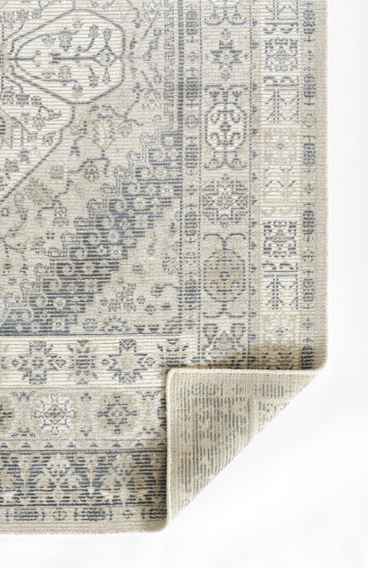 Grey distressed oriental-style area rug with intricate floral border and rolled corner.