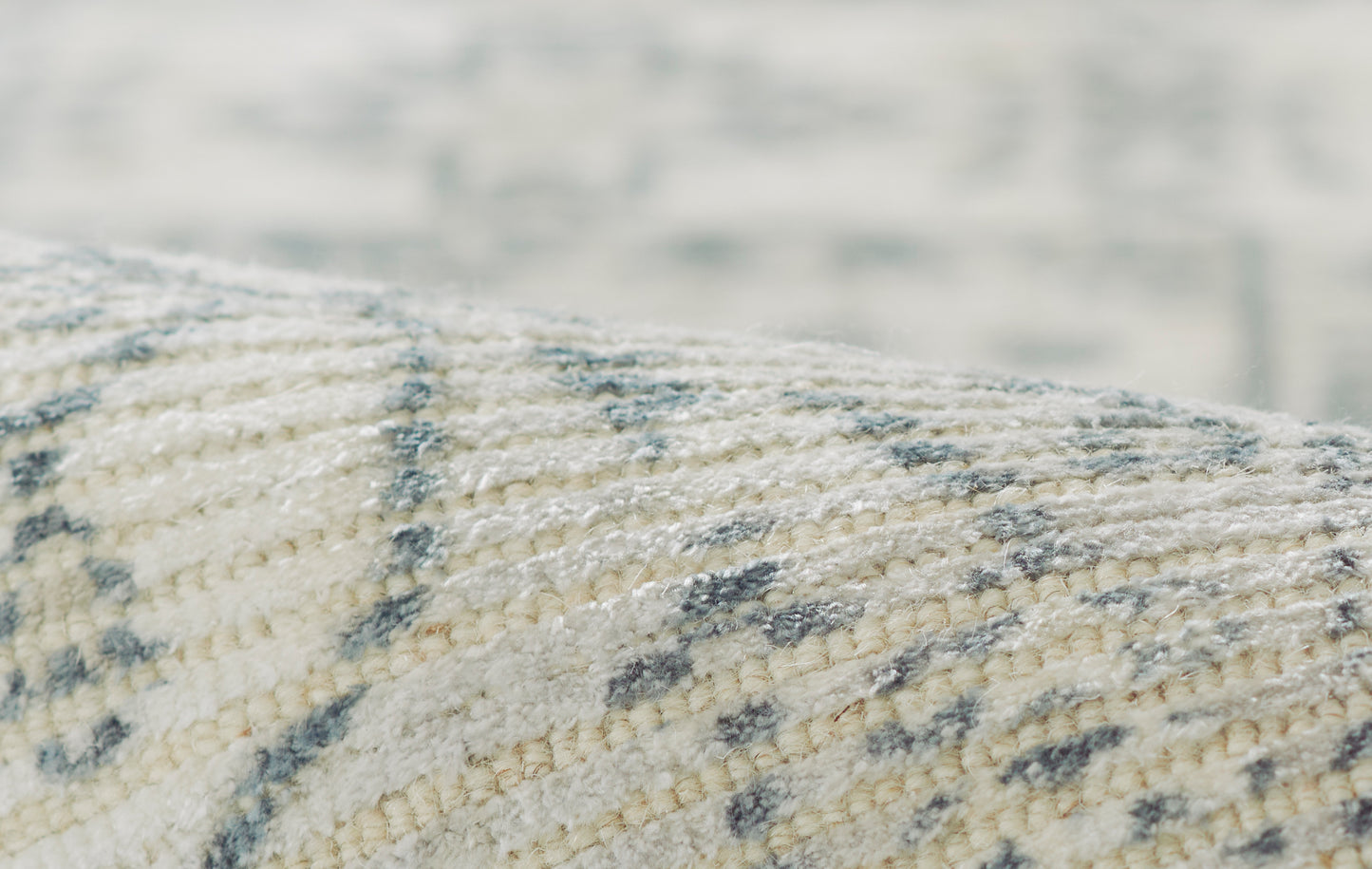 Close-up of a cream and gray woven rug with soft texture and subtle geometric pattern.