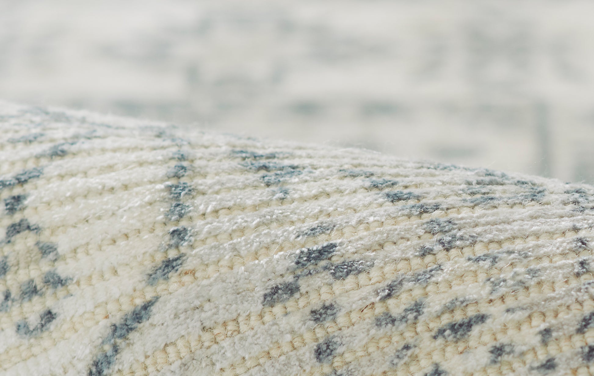 Close-up of a cream and gray woven rug with soft texture and subtle geometric pattern.