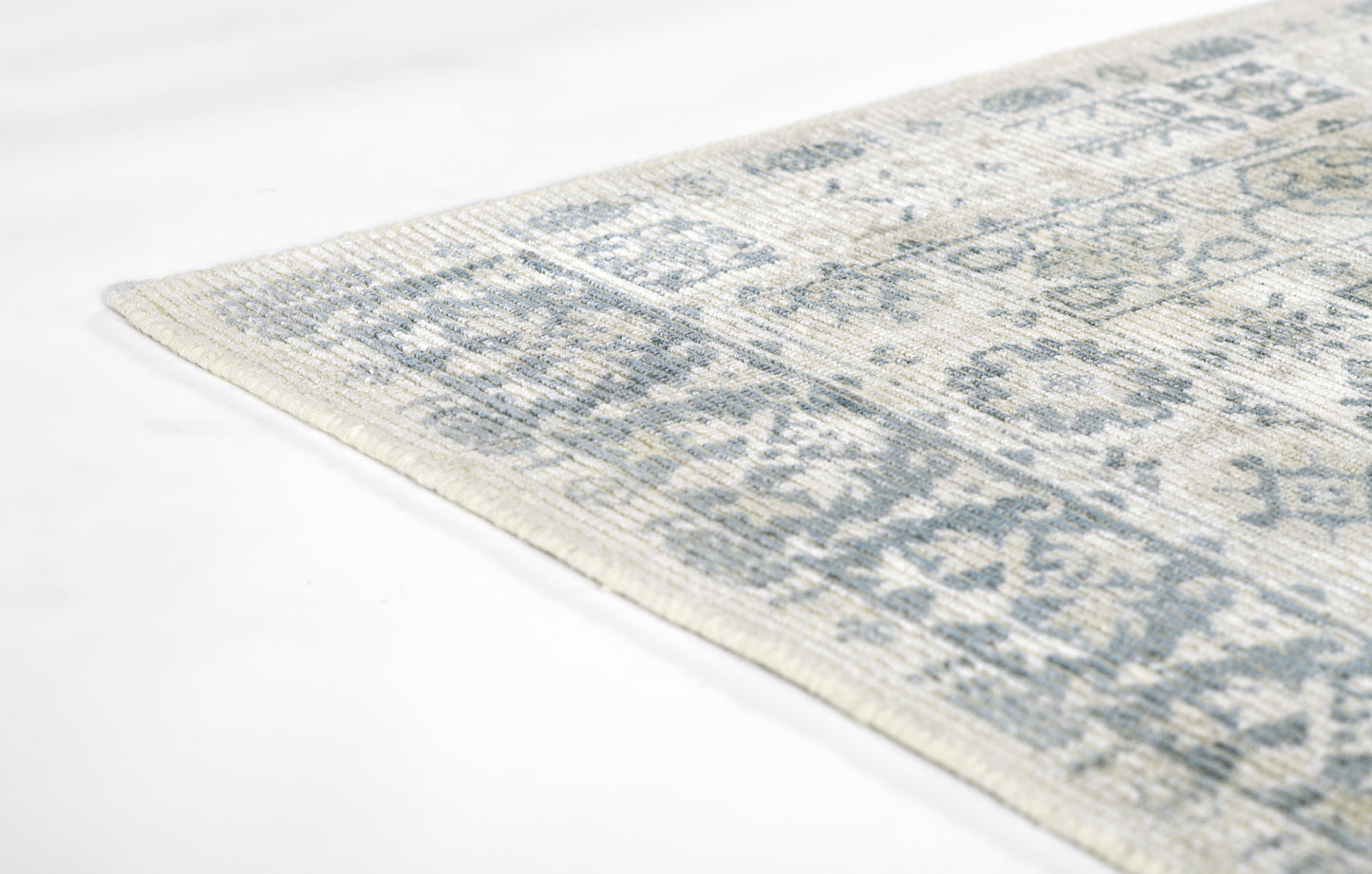 Light ivory and gray oriental rug with distressed blue-gray floral motifs; corner view.