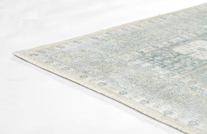 Rectangular blue-gray distressed area rug with ivory geometric pattern; modern vintage style.