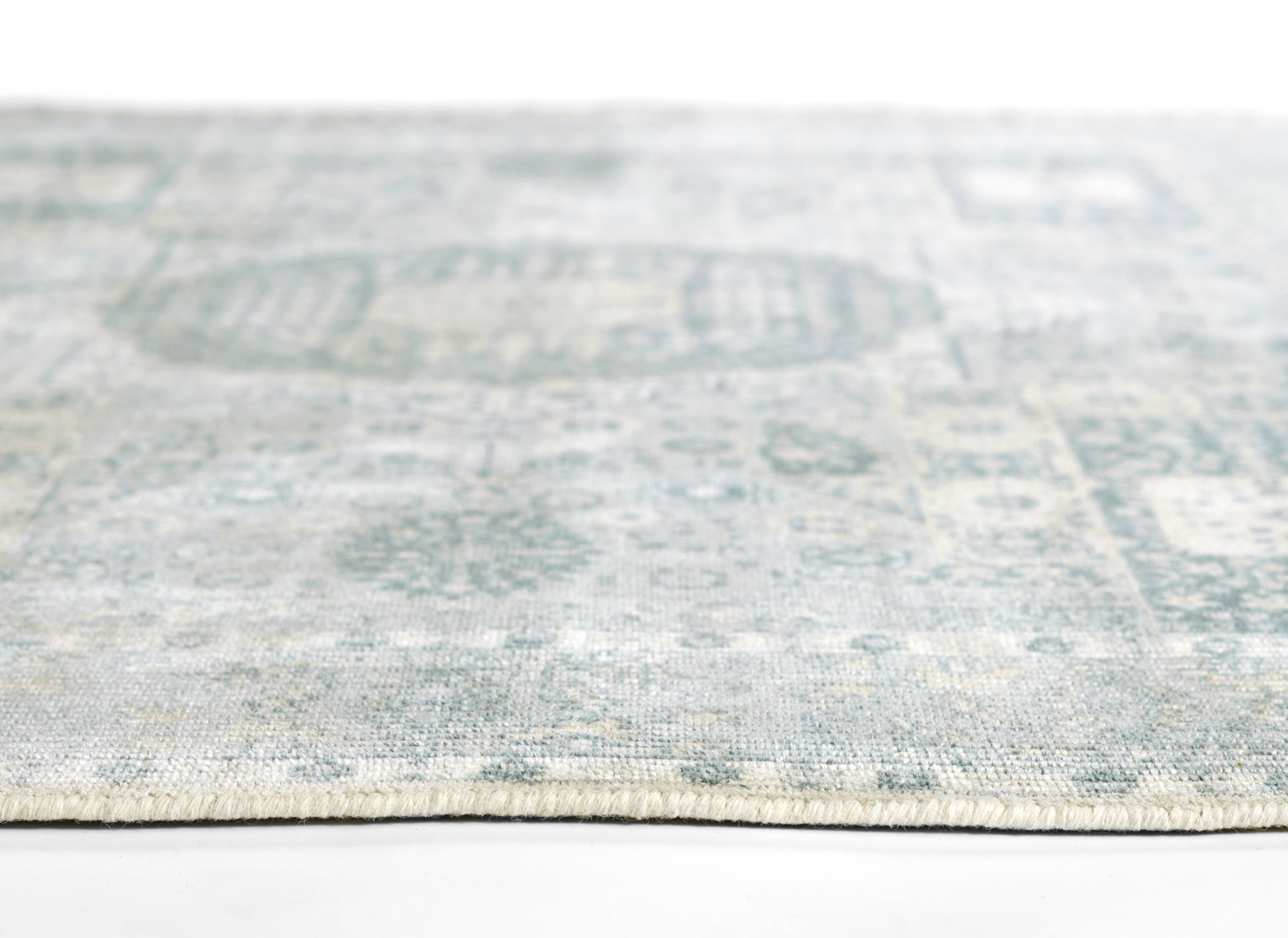 Light blue and grey patterned woven rug close-up with fringe along edge.