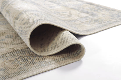 Beige-gray oriental rug with blue floral pattern, woven texture, rolled corner.