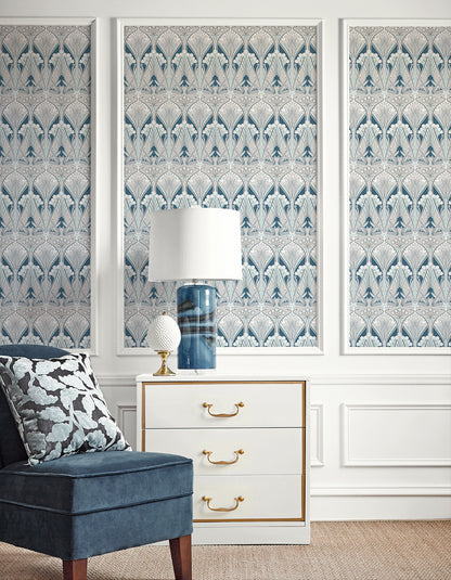 Blue damask wallpaper triptych, white dresser with gold handles, blue glass lamp, decor orb, navy velvet chair
