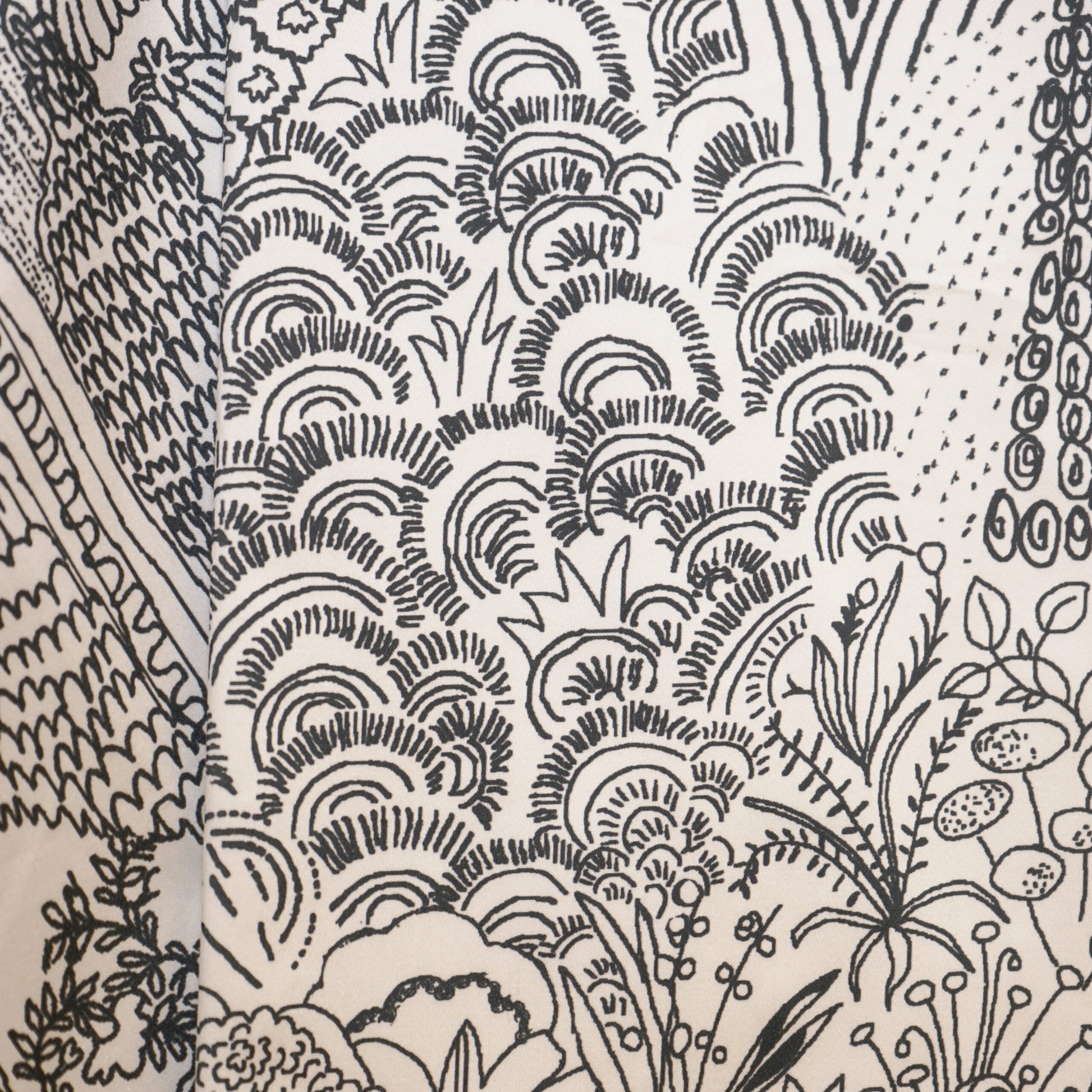 Monochrome etching-style botanical print on fabric featuring trees, leaves and swirling cloud-like arches.