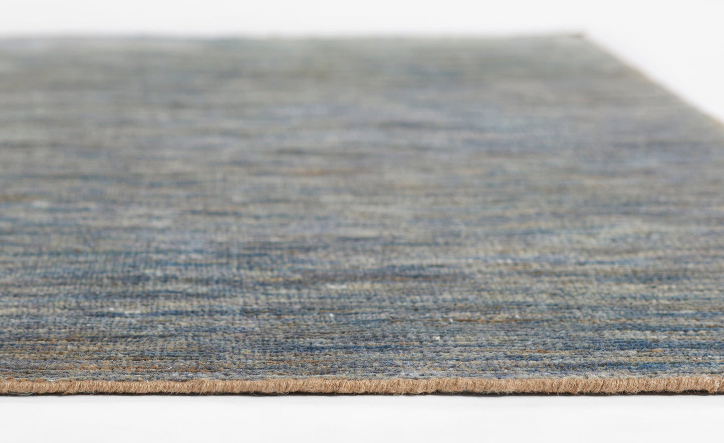 Blue-gray textured rug edge with tan underside, woven fibers for a modern living space.