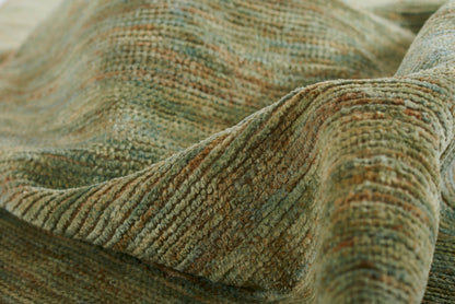 Woven rug in olive green and brown tones with ribbed texture and soft drape, earthy rustic style.